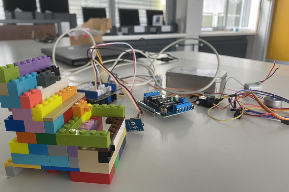 Colorful LEGO brick structure connected to an Arduino-like circuit on a lab bench.