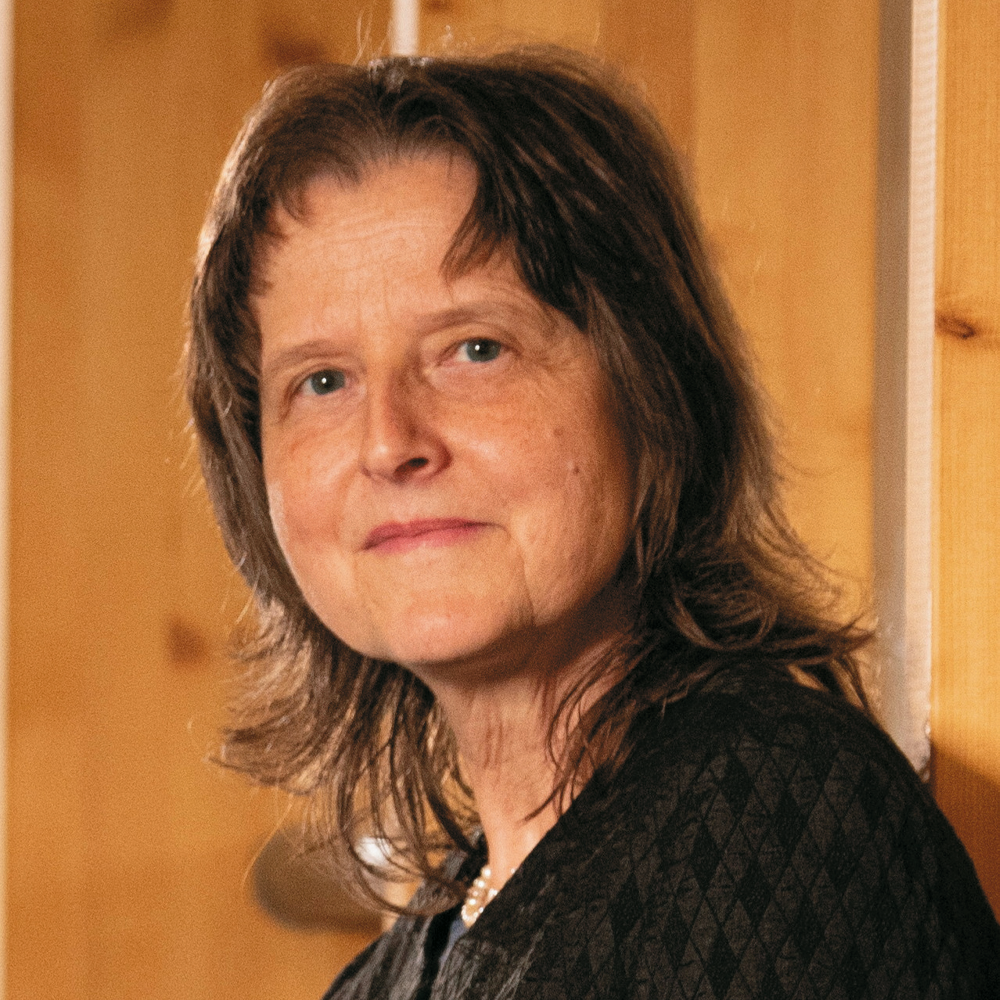 Portrait of a middle-aged woman with brown hair, wearing a dark textured garment.